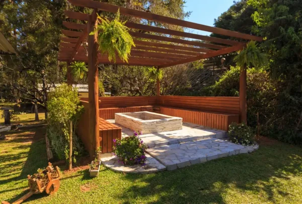 planning-permission-patio-deck-wall-kildare Spacious wooden gazebo in a lush garden setting with green foliage and stone flooring