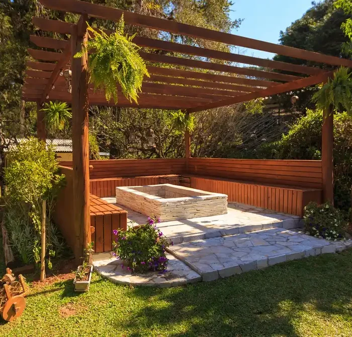 Spacious wooden gazebo in a lush garden setting with green foliage and stone flooring